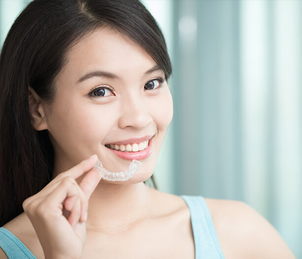 young woman holding clear aligner