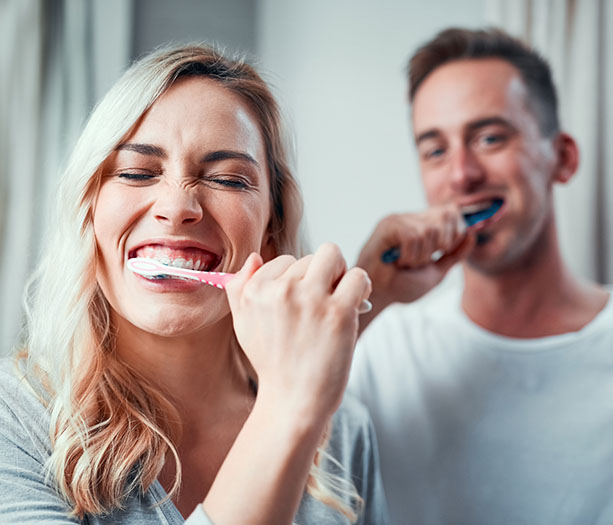 a young couple brushing their teeth together