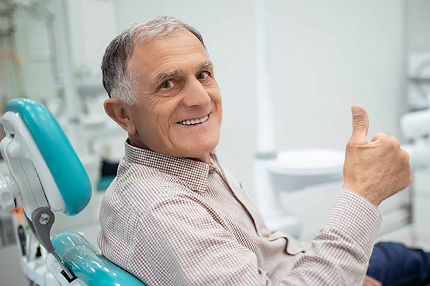 Mature man in the dental chair giving the thumbs up sign.