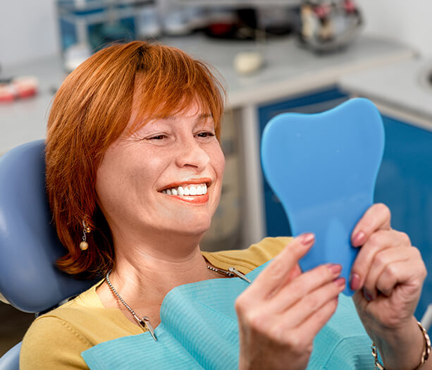 woman looking at her smile in a mirror