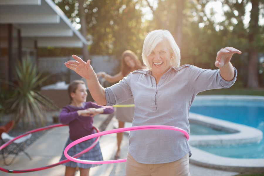 Woman smiles while hula hooping with her granddaughter after replacing missing teeth