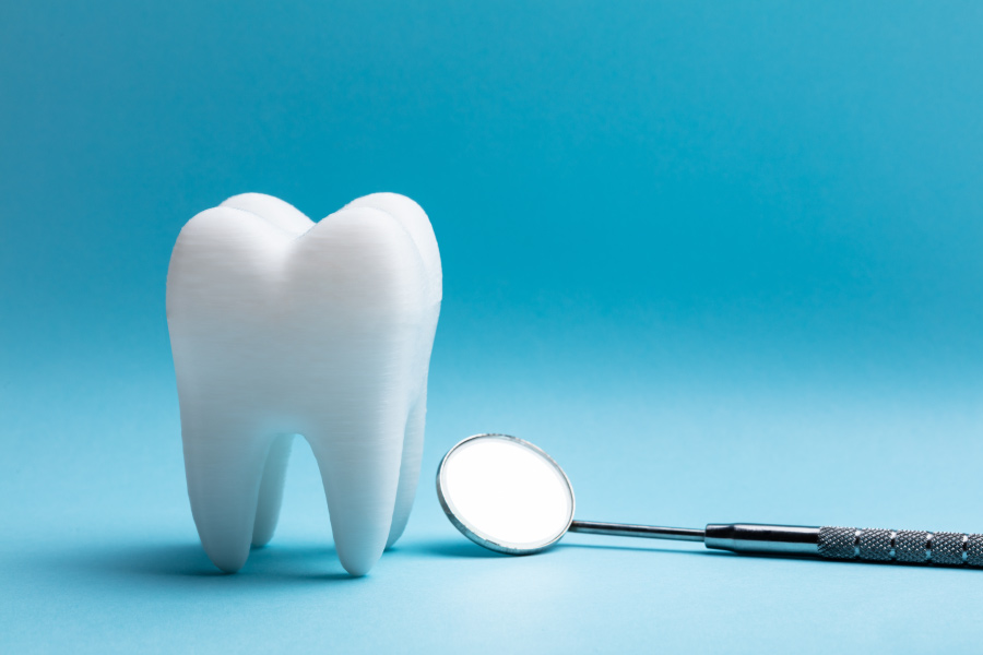 White tooth next to a special dental mirror on a blue background to symbolize a tooth extraction