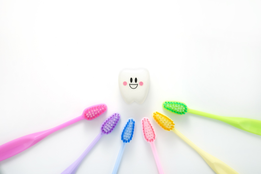Different colored toothbrushes next to a tooth to symbolize different kinds of dentists
