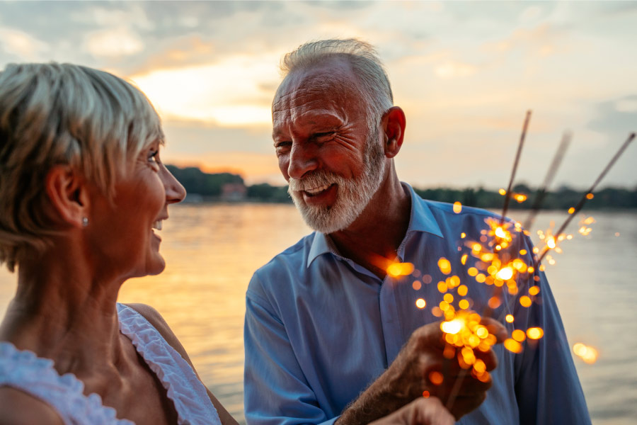 A couple smiles with dental implants while holding sparklers for the New Year in Harrisonburg, VA