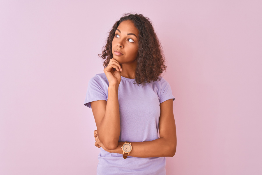 Curly-haired Black woman in a lavender shirt wonders if she should see a prosthodontist