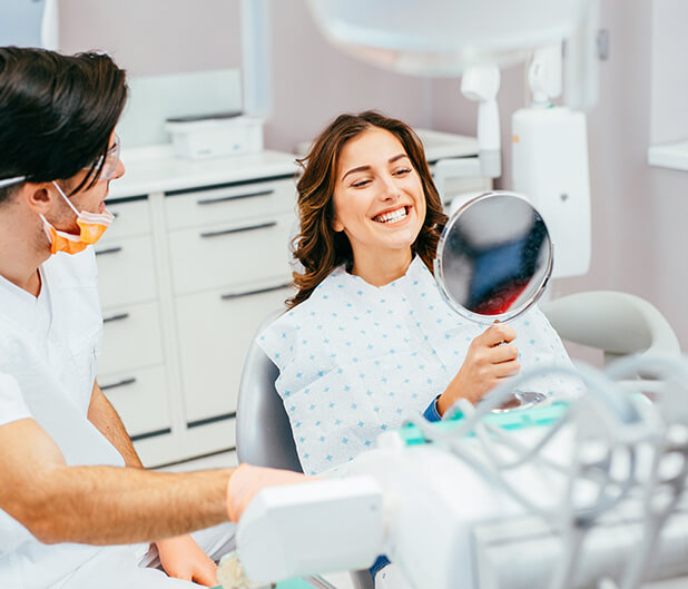 dental patient admiring her smile in a mirror
